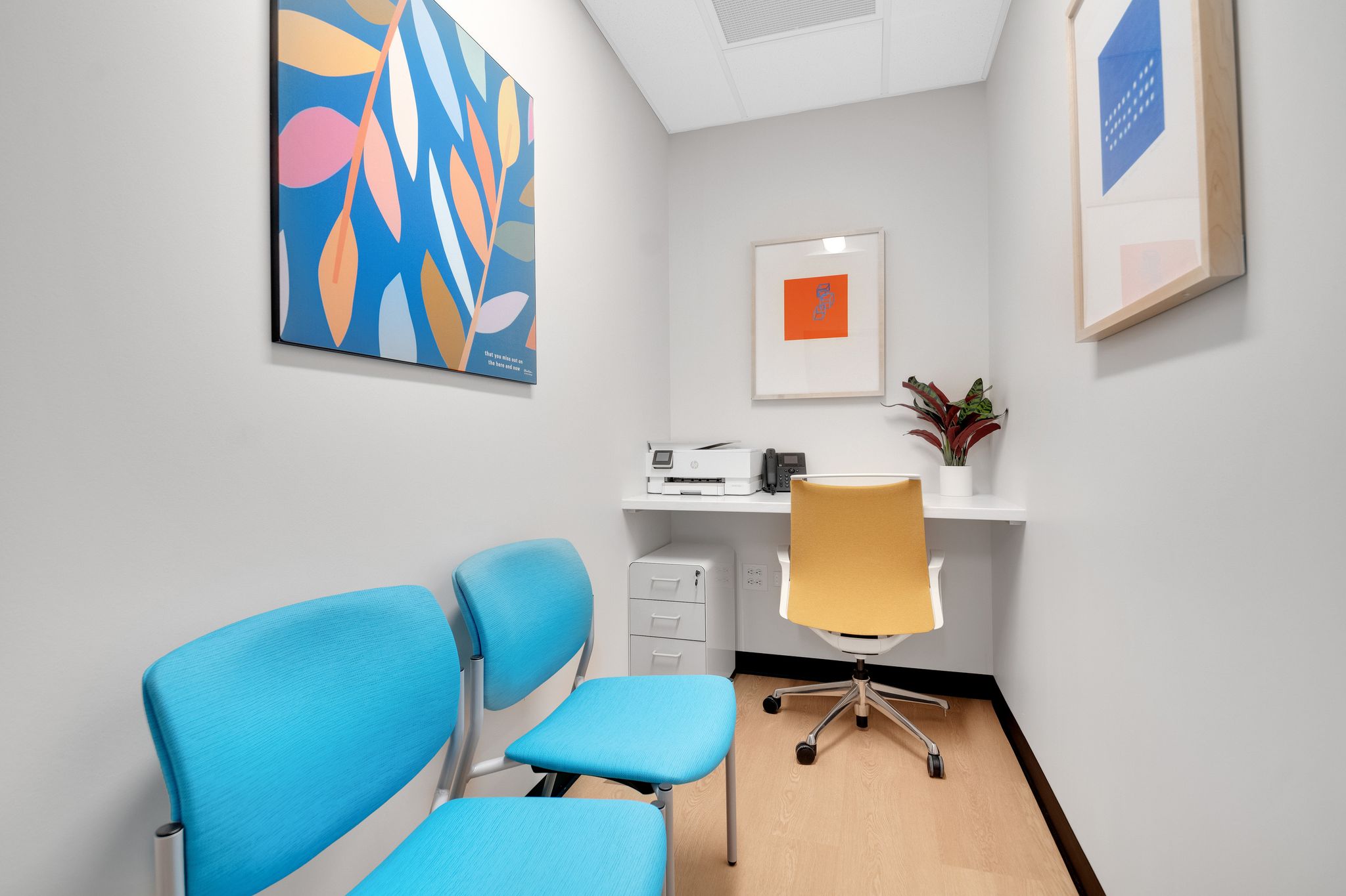 Individual meeting room with desk and two blue chairs