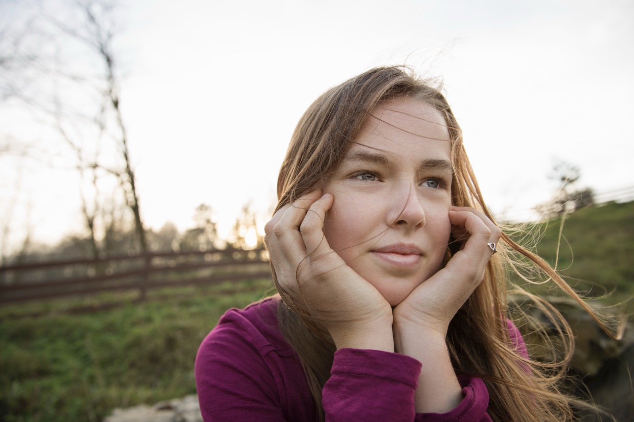 Saugerties, NY,U.S.,A young girl with her chin in her hands, leaning on a fence at an animal sanctuary.