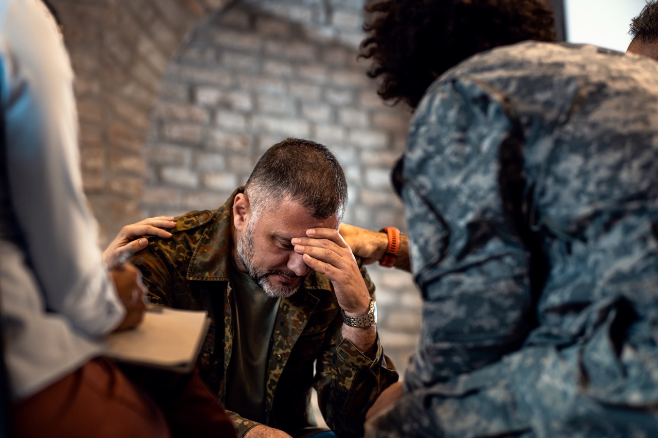 Group of diverse veterans talking during PTSD support group.