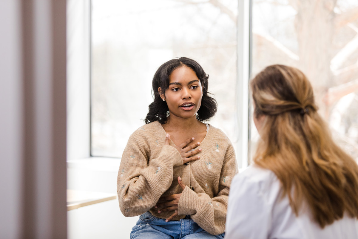 University student motions towards her chest as she describes the discomfort she has been experiencing