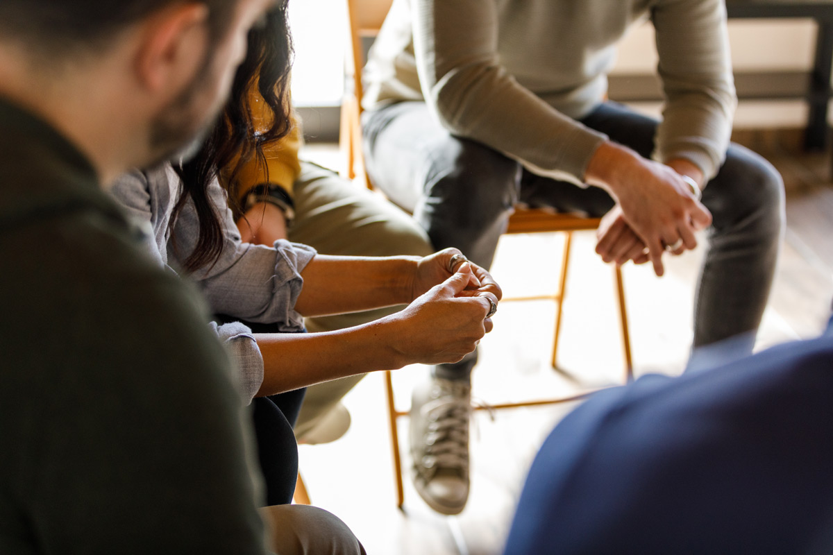 People anxiously fidgeting their hands while sharing stories during a group therapy session