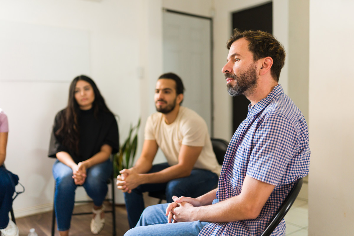 Adults participating in support group therapy meeting